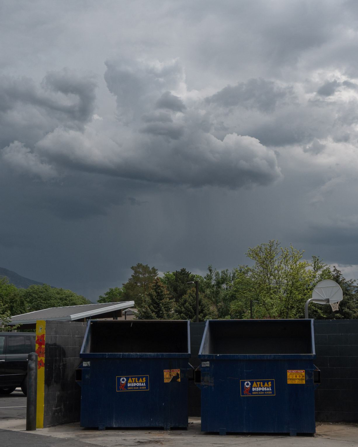 Rain clouds over two blue dump bins